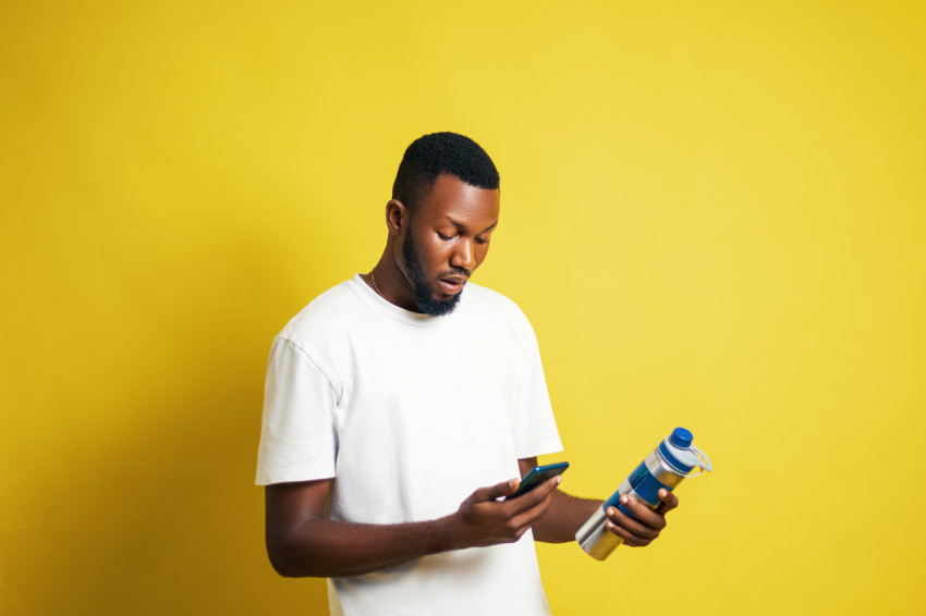 Man with bottle pressing his phone