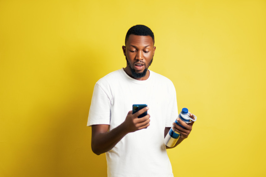 Man with water bottle pressing phone