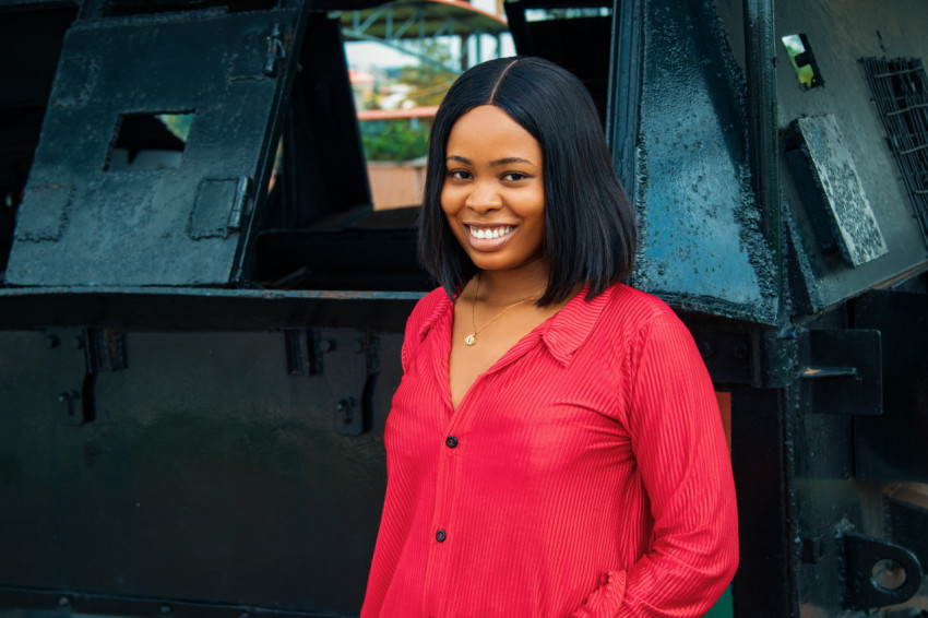 Girl smiling in front of an armoured tank