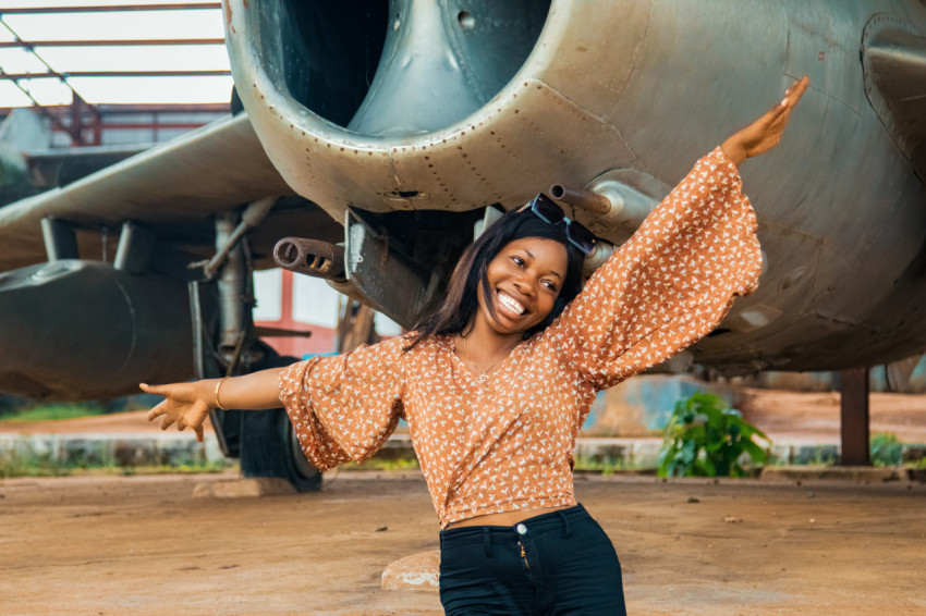 A lady smiling under a war plane