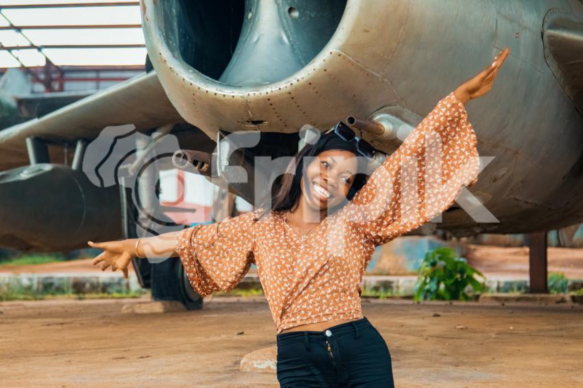A lady smiling under a war plane