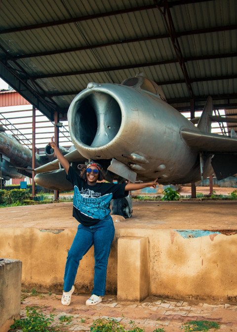 A lady smiling under a war plane A