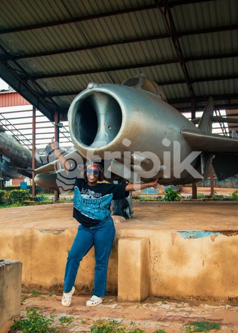 A lady smiling under a war plane A