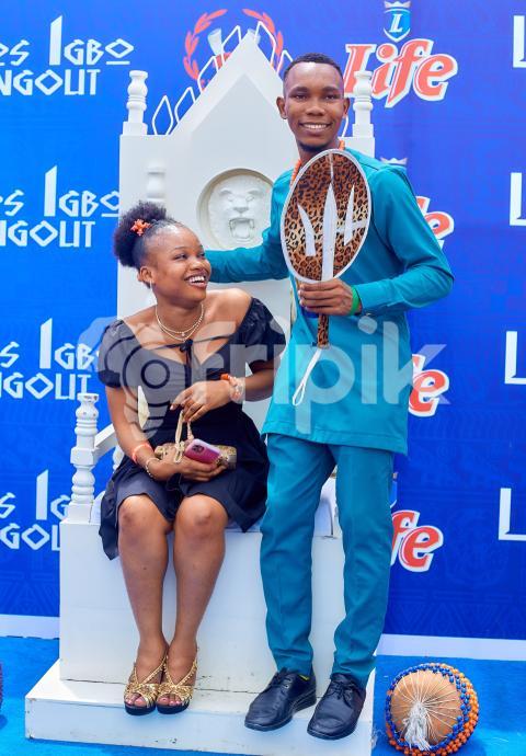 A boy standing beside a girl sitting