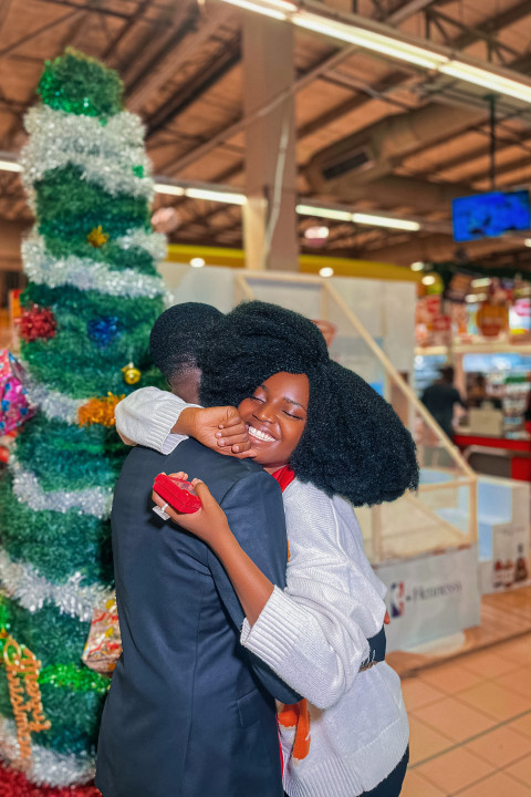 Boy and girl hugging in front of a christmas tree