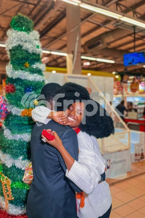Boy and girl hugging in front of a christmas tree
