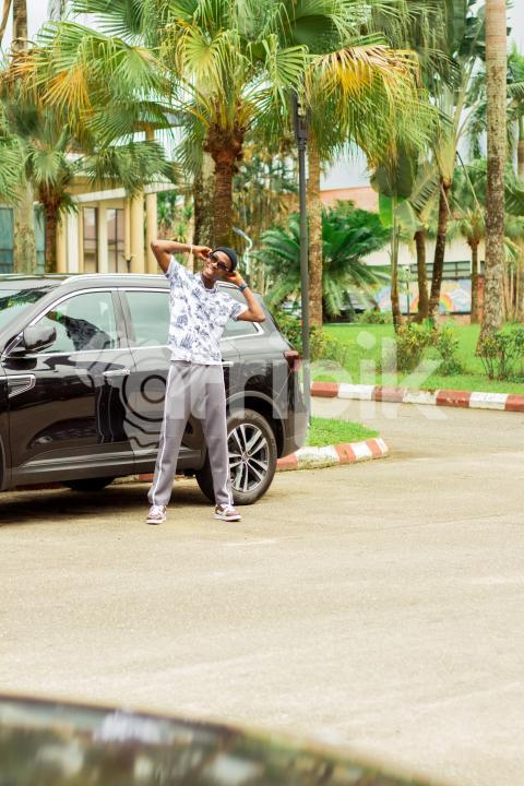 A happy boy in front of car