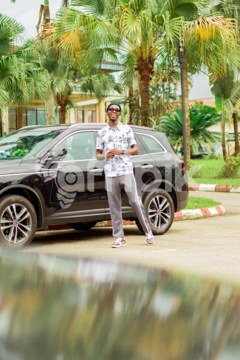 A happy boy standing in front of car