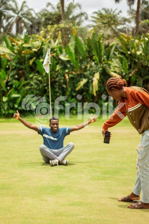 Girl takes a snapshot of sitting boy